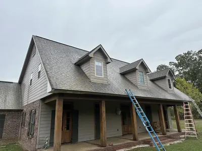 Ladders set up on the front porch of a two-story home during a house wash