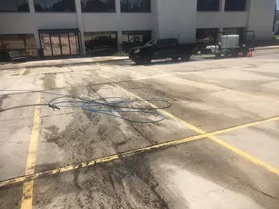 Concrete parking lot partly pressure washed, showing clean and dirty sections
