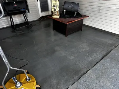 Freshly cleaned concrete patio with a surface cleaner in the corner