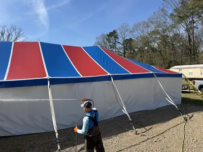 ProWash360 tech soft washing the side of a large red, white and blue event tent