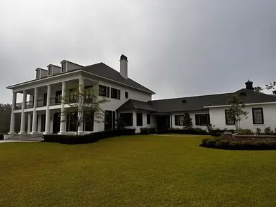 Large white two-story home with columns and a wide lawn after an exterior wash
